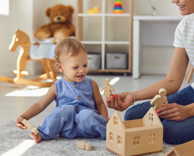 Joyful Young Nanny and Little Kid Playing with Wooden Blocks in Cozy Nursery Room Joyful Young Nanny and Little Kid Playing with Wooden Blocks in Cozy Nursery Room